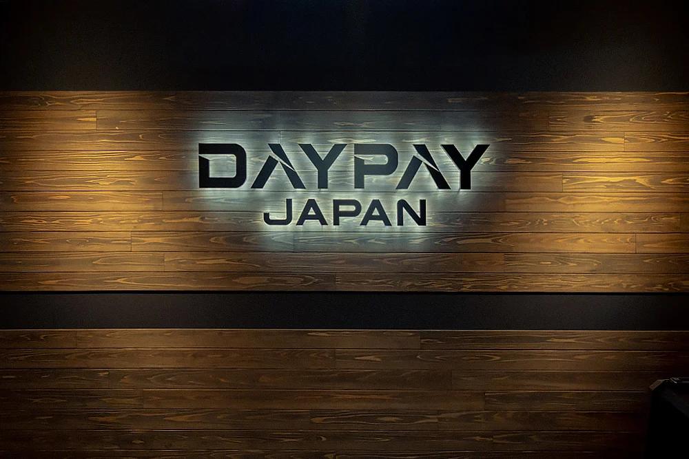 木目調の壁面に「DAYPAY JAPAN」の立体的なロゴ看板が掲示されているオフィスエントランス