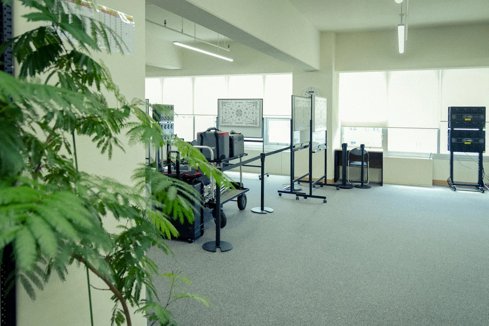 明るい窓際の執務スペースに観葉植物と機材が配置されたデイペイレンタル東京支店のオフィス内観