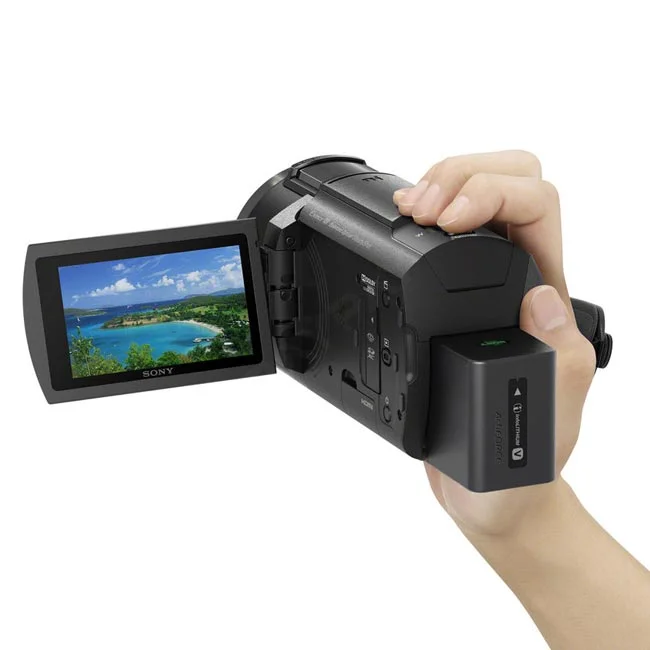 使用者手持 Sony FDR-AX43 數位相機側面特寫，可見翻轉螢幕顯示風景畫面與電池配件，提供優質的相機出租與器材出租服務選擇。- 日付租賃 DAYPAY RENTAL