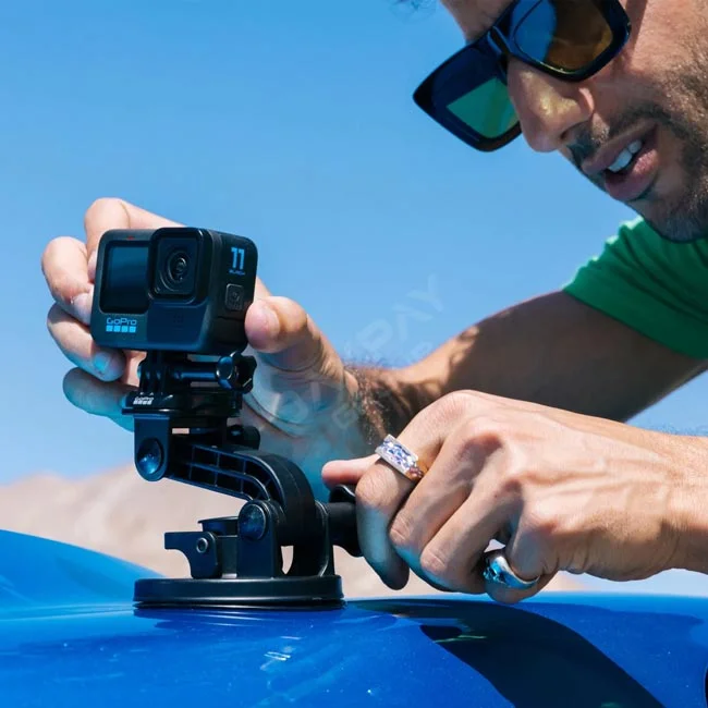 使用者正在將 GoPro Suction Cup 強力吸盤安裝於車輛平整表面，並搭配快拆短臂調整相機角度